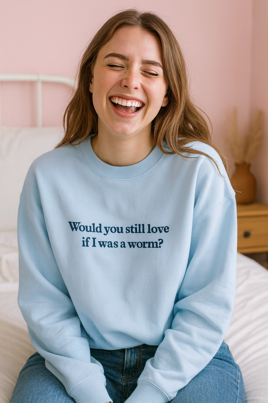 A smiling woman wearing a light blue sweatshirt with the text "Would you still love if I was a worm?"