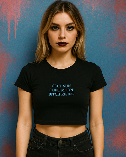 A woman wearing a black crop top with text on it stands against a blue background with splatters.
