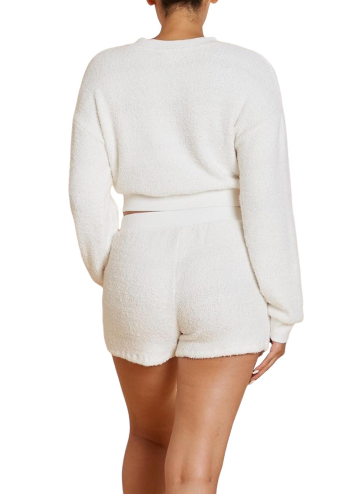 a woman wearing a white sweater and shorts