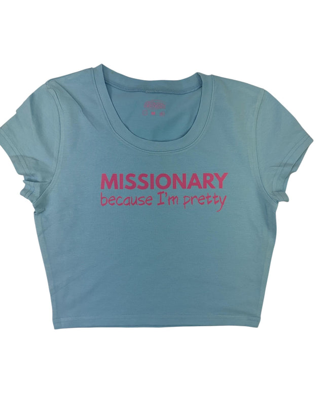 A light blue cropped t-shirt with the text "MISSIONARY because I'm pretty" printed on it in pink.