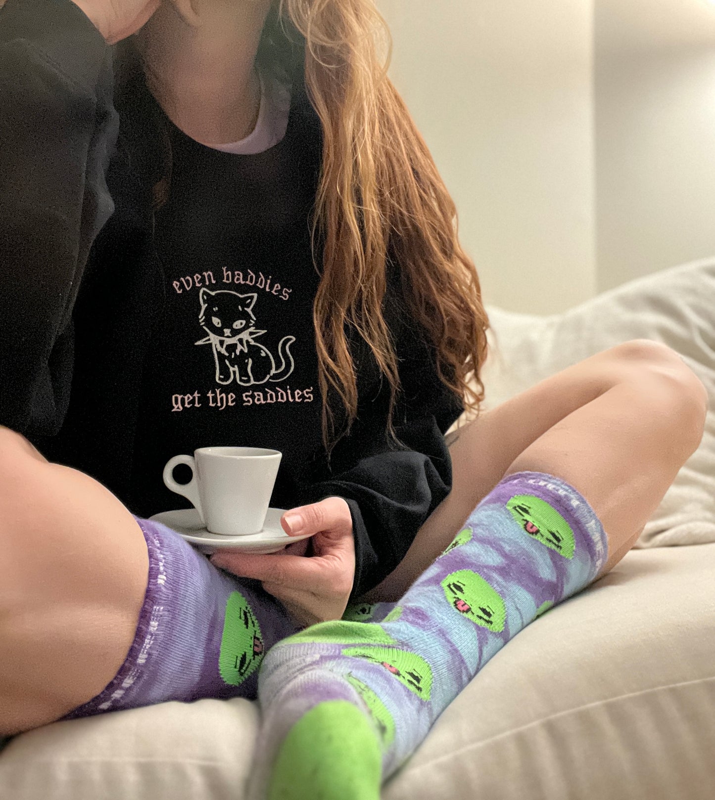 a woman sitting on a couch holding a cup of coffee