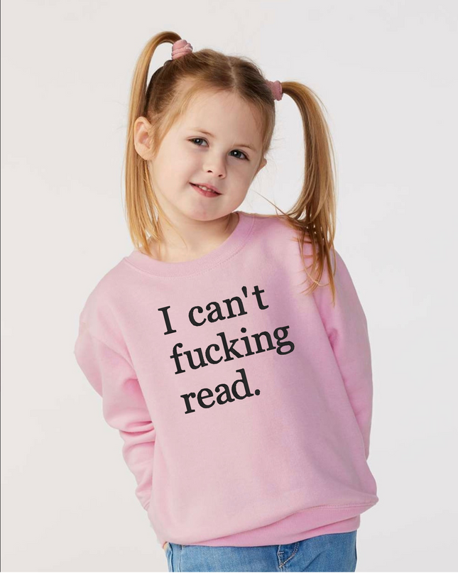 A young girl with pigtails wearing a pink sweatshirt with the text "I can't fucking read" printed on it.