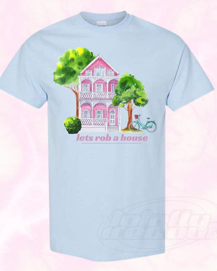 a blue t - shirt with a pink house and trees on it
