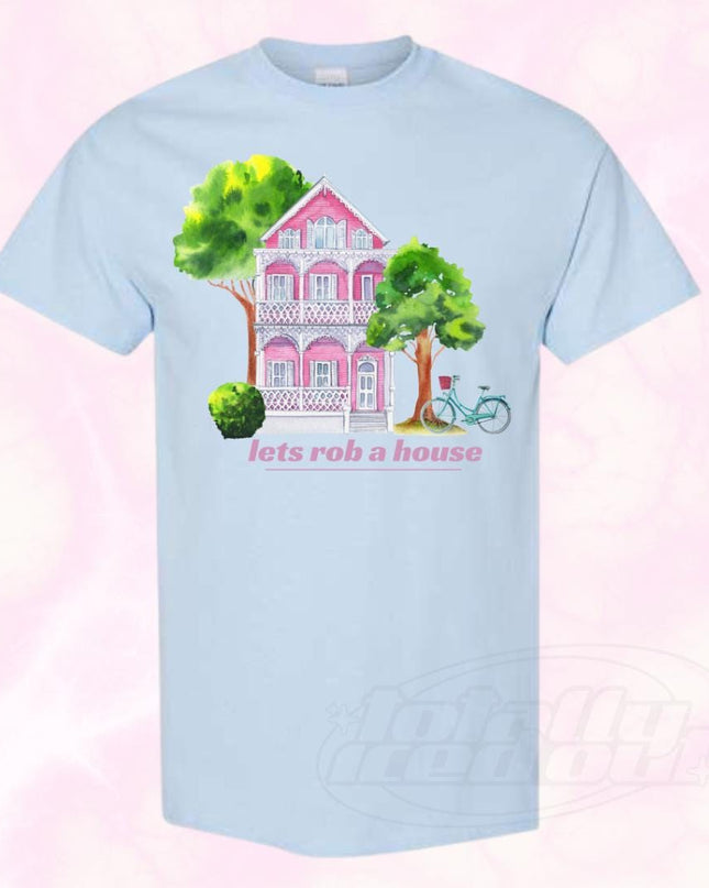 a blue t - shirt with a pink house and trees on it