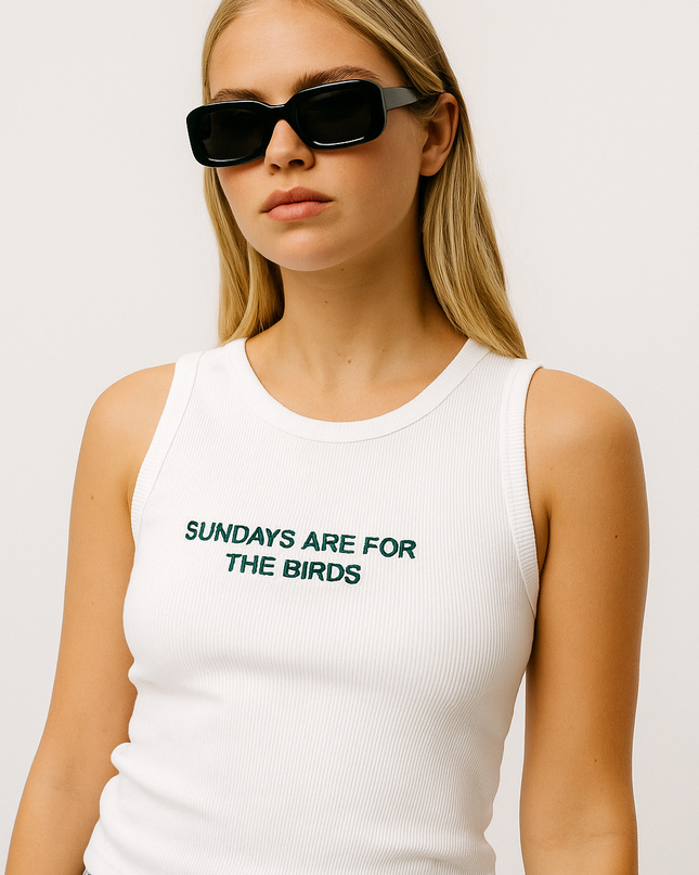 A woman wearing a white tank top with the text "SUNDAYS ARE FOR THE BIRDS" printed on it.