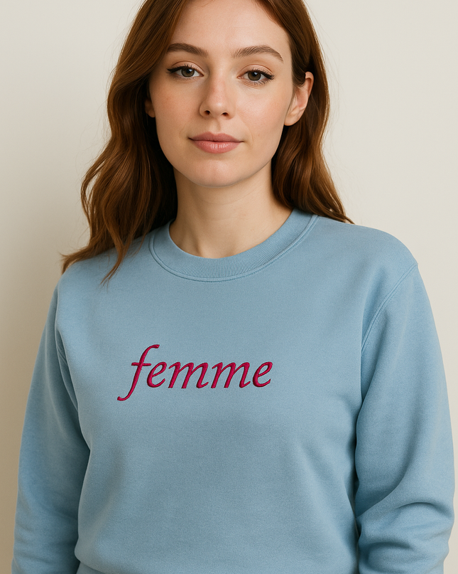 A young woman with long brown hair wearing a light blue sweatshirt with the word "femme" printed on it.