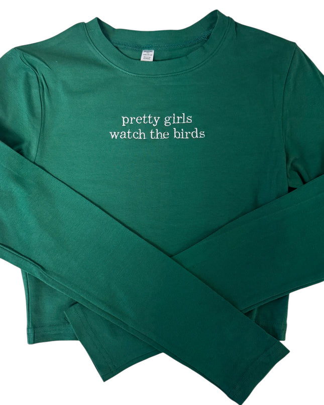 A green long-sleeved shirt with the text "Pretty girls watch the birds" printed on it.