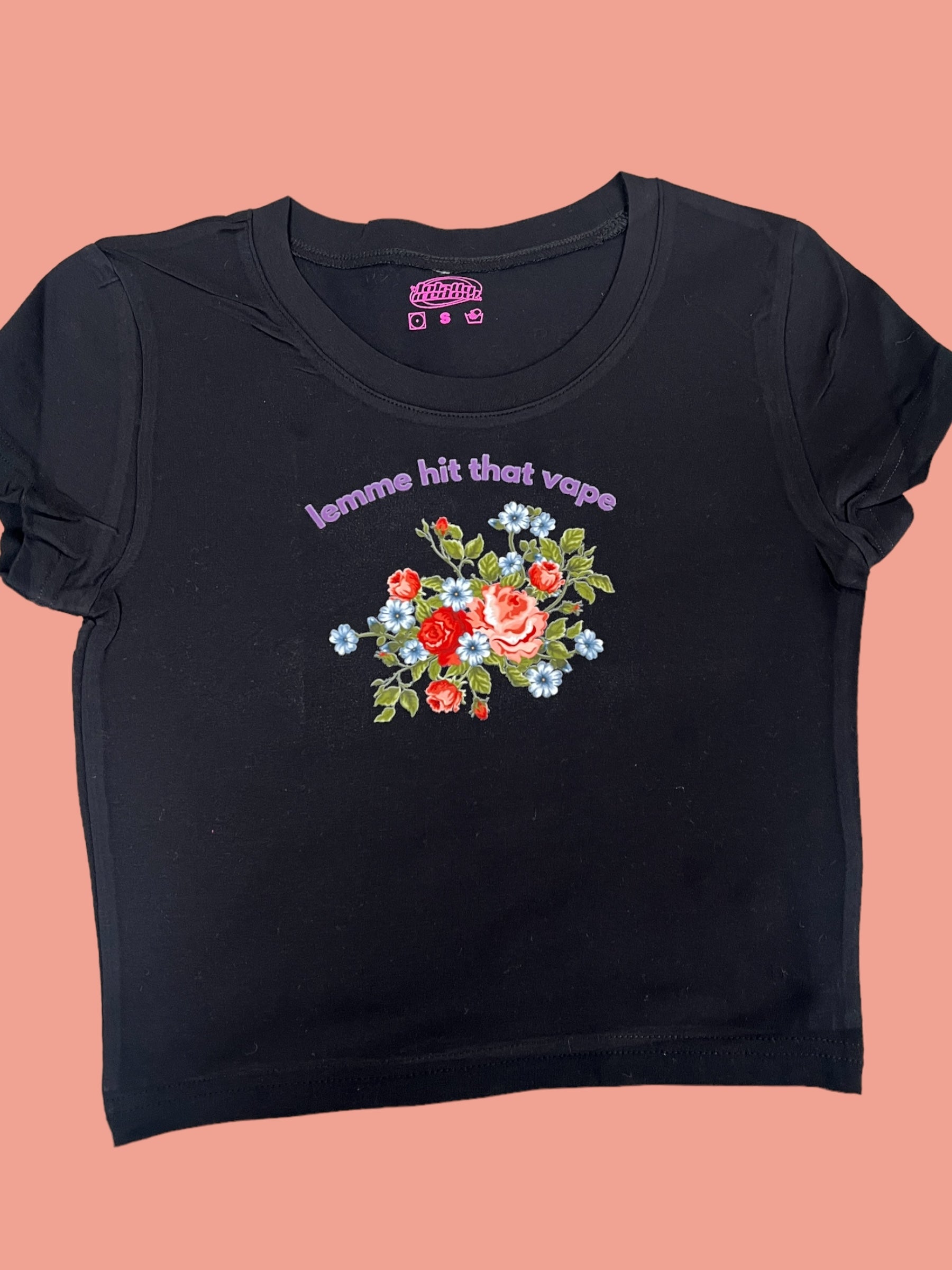 A black t-shirt with a floral design and text printed on it.