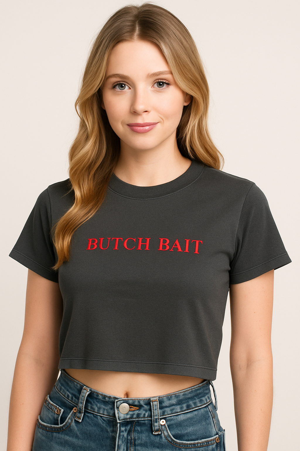 A young woman with long blonde hair wearing a black crop top with the text "BUTCH BAIT" printed on it.