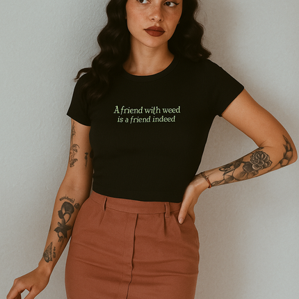 A woman with long dark hair wearing a black t-shirt with text and a brown skirt stands against a white background.