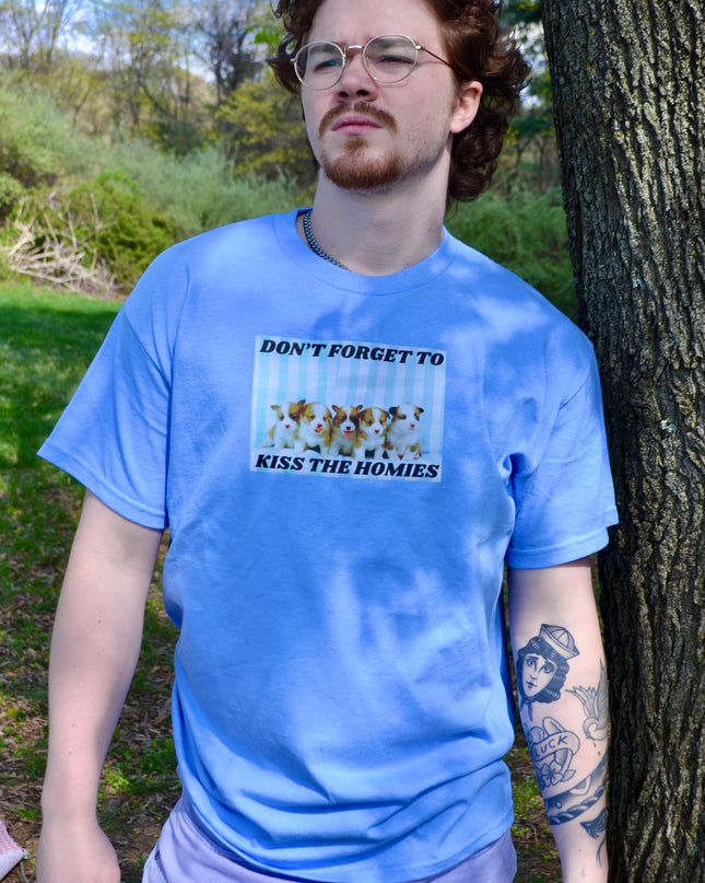 a man standing next to a tree wearing a blue shirt