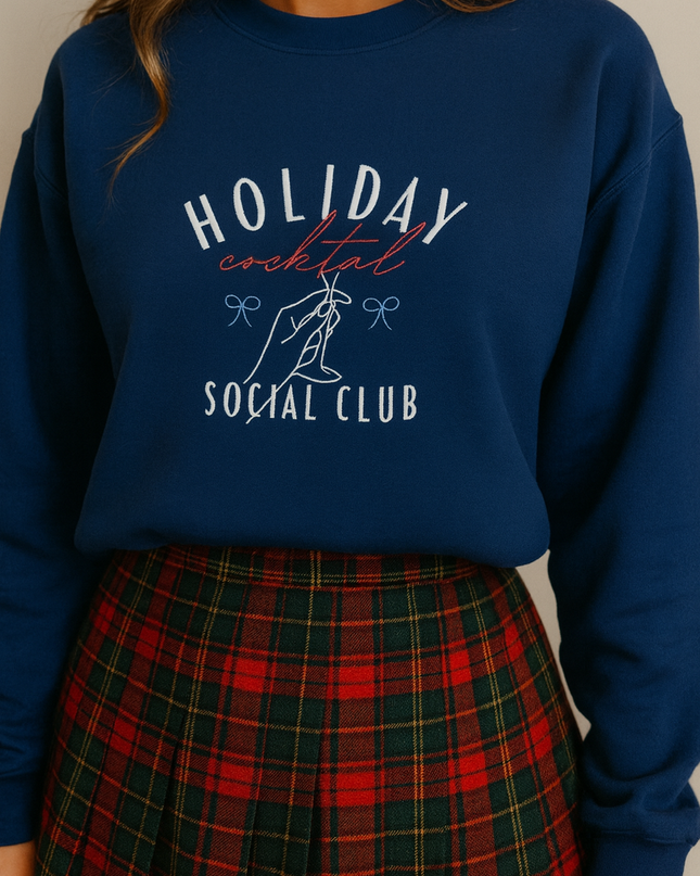 A woman wearing a navy blue sweatshirt with the text "HOLIDAY COCKTAIL SOCIAL CLUB" printed on it, paired with a plaid skirt.