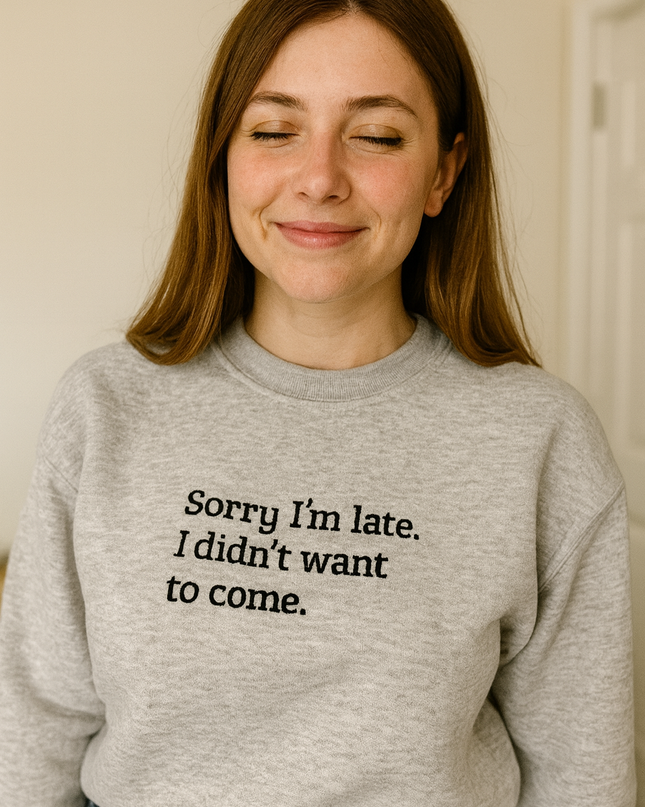 A woman wearing a gray sweatshirt with the text "Sorry I'm late. I didn't want to come." printed on it.