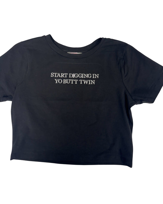 A black t-shirt with the text "START DIGGING IN YO BUTT TWIN" printed on it.