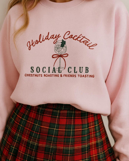 A woman wearing a pink sweatshirt with a graphic design and text, paired with a plaid skirt.