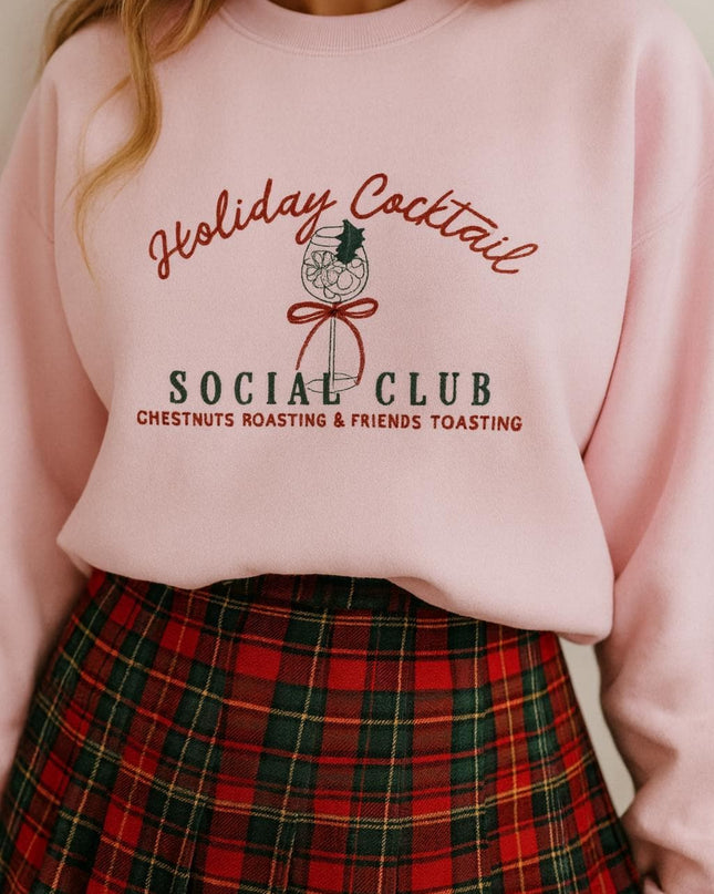 A woman wearing a pink sweatshirt with a graphic design and text, paired with a plaid skirt.
