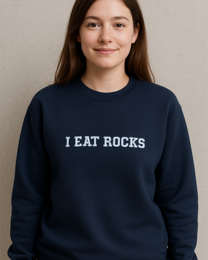 A young woman wearing a navy blue sweatshirt with the text "I EAT ROCKS" printed on it.