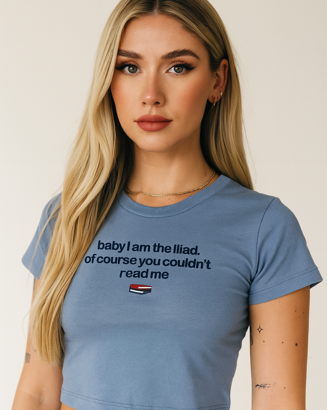 A young woman with long blonde hair wearing a blue crop top with text on it.