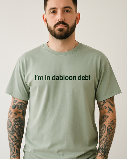 A man with a beard wearing a green t-shirt with the text "I'm in dabloon debt" printed on it.