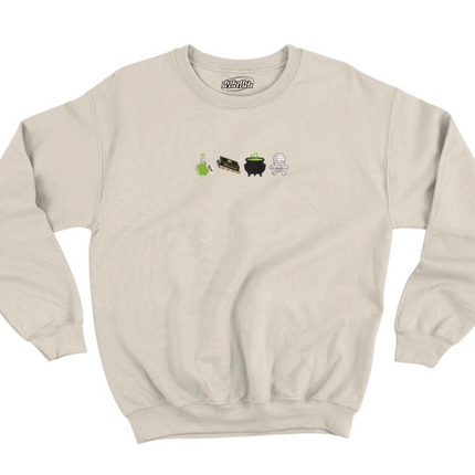 A beige sweatshirt with a graphic design featuring four small icons representing a witch's cauldron, a black cat, a green plant, and a skull.