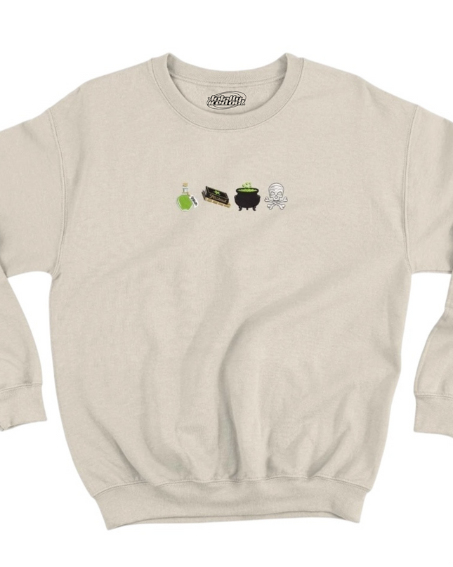 A beige sweatshirt with a graphic design featuring four small icons representing a witch's cauldron, a black cat, a green plant, and a skull.