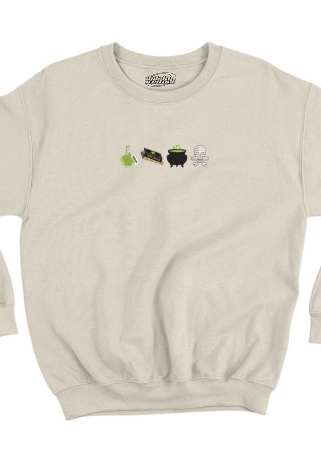 A beige sweatshirt with a graphic design featuring four small icons representing a witch's cauldron, a black cat, a green plant, and a skull.