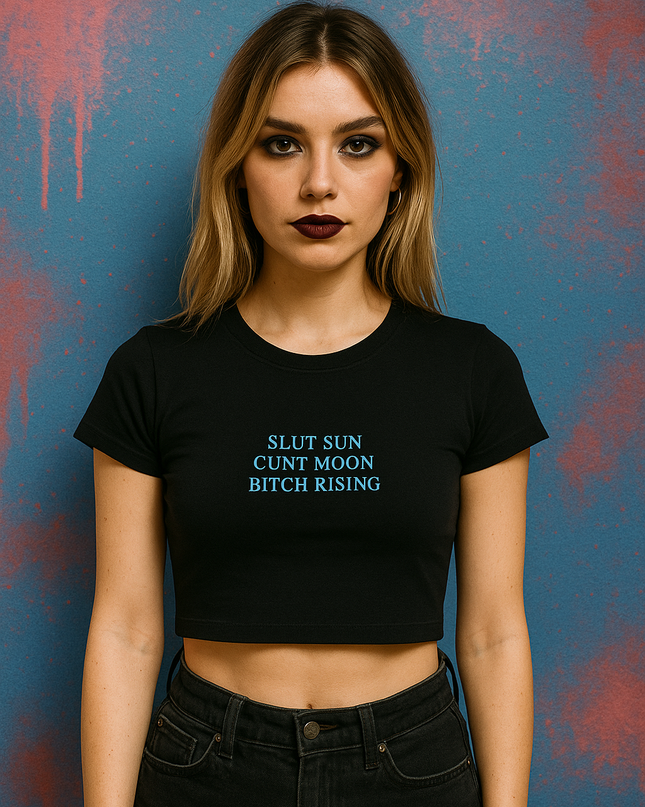 A woman wearing a black crop top with text on it stands against a blue background with splatters.