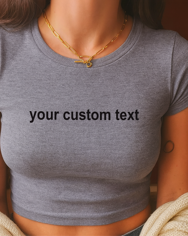 A woman wearing a gray crop top with the text "your custom text" printed on it.