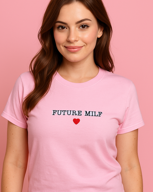 A woman wearing a pink t-shirt with the text "FUTURE MILF" and a red heart symbol printed on it.