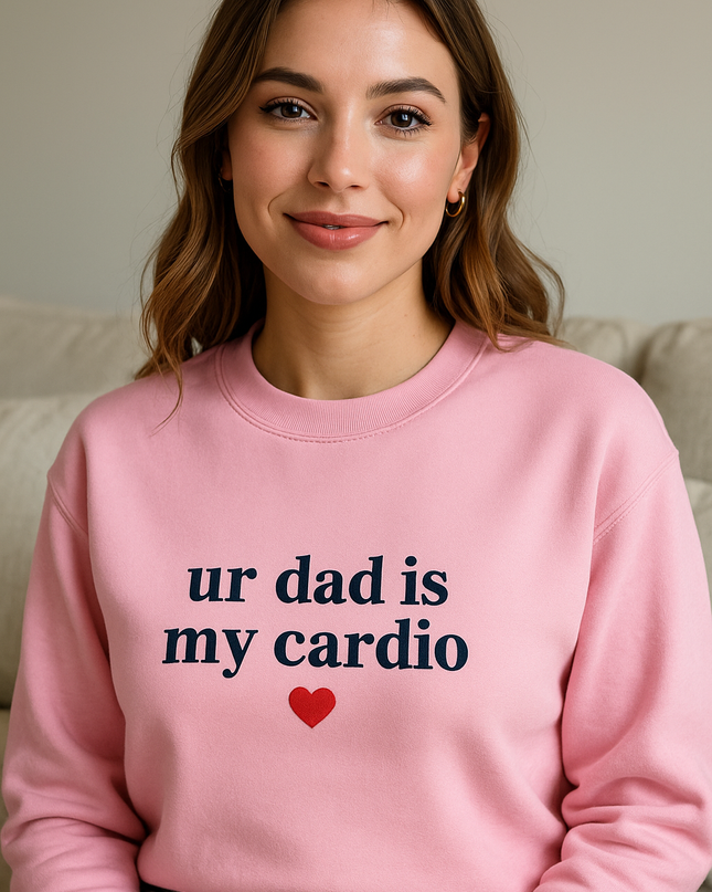 A woman wearing a pink sweatshirt with the text "ur dad is my cardio" and a red heart symbol.