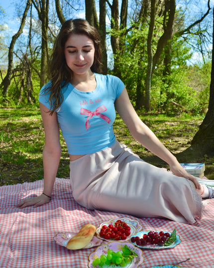 a woman sitting on a picnic blanket with a plate of fruit