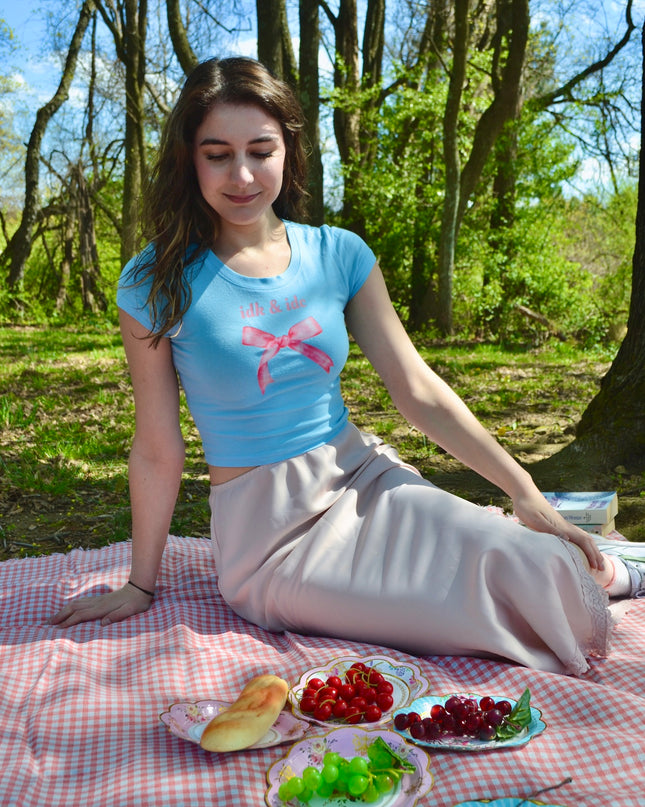 a woman sitting on a picnic blanket with a plate of fruit