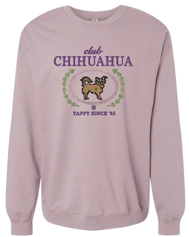 A pink sweatshirt with a graphic design featuring a chihuahua and the text "club CHIHUAHUA" and "YAPPY SINCE '85".