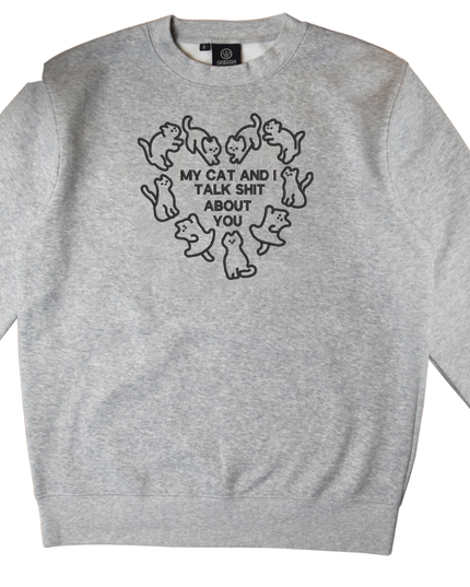 A gray sweatshirt with a black graphic design on the front. The design features a heart shape with the text "MY CAT AND I TALK SHIT ABOUT YOU" written inside it.