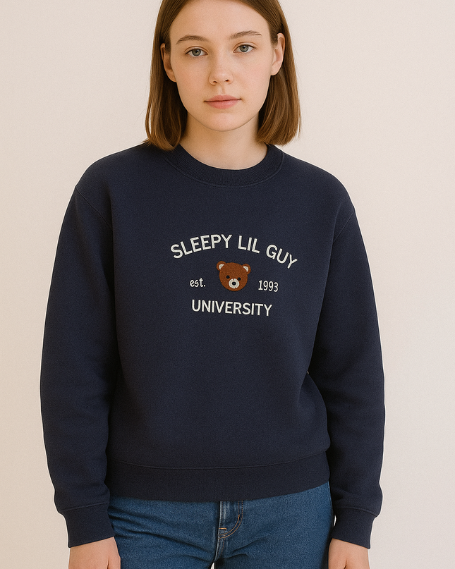 A young woman wearing a navy blue sweatshirt with the text "SLEEPY LIL GUY est. 1993 UNIVERSITY" printed on it.