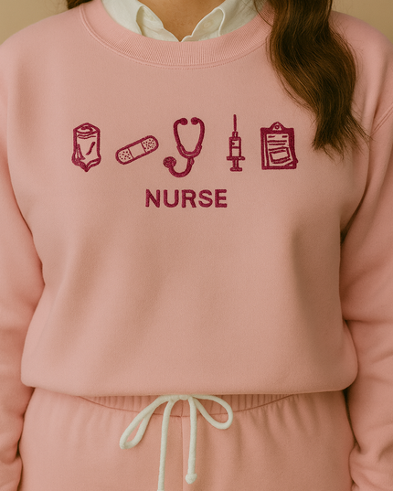 A woman wearing a pink sweatshirt with the word "NURSE" printed on it, along with various medical icons such as a stethoscope, syringe, and bandages.