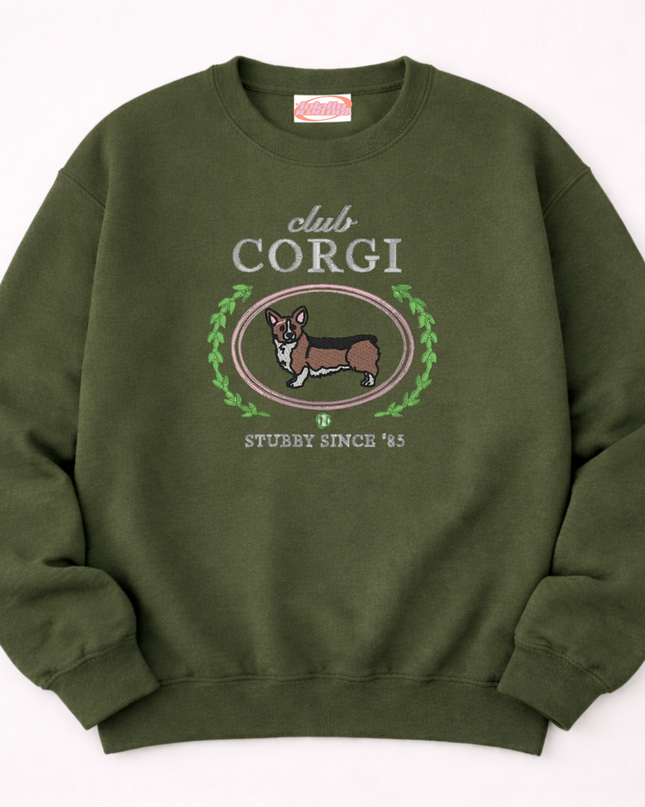 A green sweatshirt with a graphic design featuring a cartoon image of a corgi dog and the text "club CORGI" and "STUBBY SINCE '85".