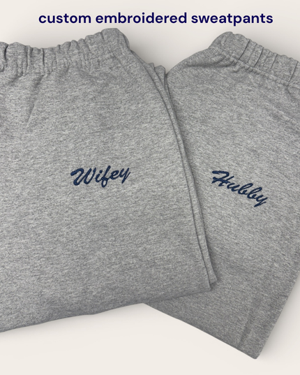 Two pairs of gray sweatpants with the names "Wifey" and "Hubby" embroidered on them.