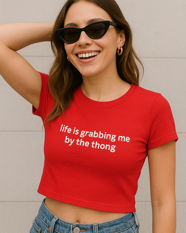 A woman wearing a red crop top and sunglasses is smiling and posing for the camera.