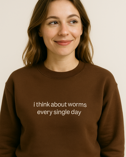 A woman wearing a brown sweater with the text "I think about worms every single day" printed on it.