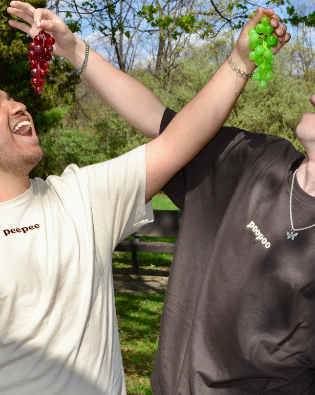 a man holding a bunch of grapes next to another man