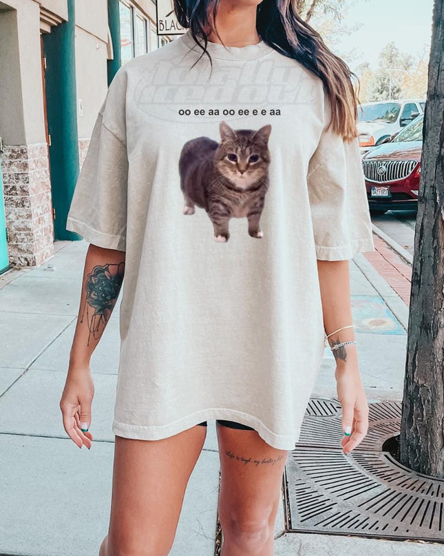 a woman standing on a sidewalk with a cat t - shirt on