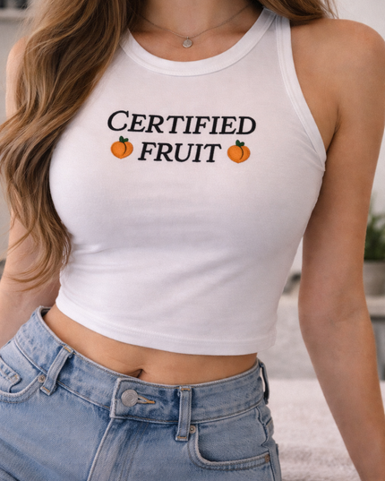 A woman wearing a white crop top with the text "Certified Fruit" printed on it, paired with denim shorts.