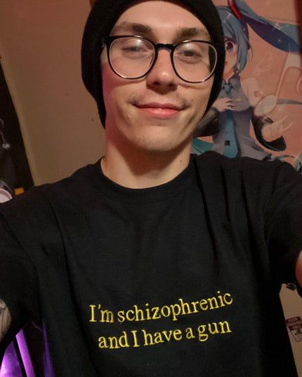 A person wearing a black t-shirt with yellow text and glasses is smiling at the camera.