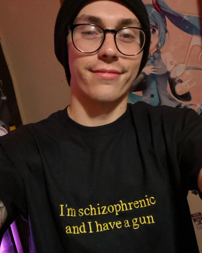 A person wearing a black t-shirt with yellow text and glasses is smiling at the camera.