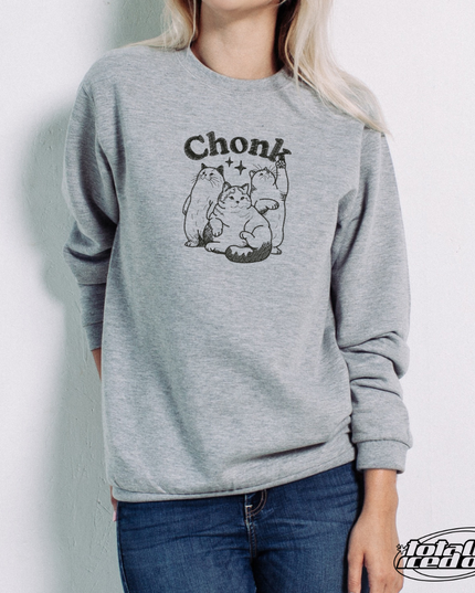 A woman wearing a gray sweatshirt with a graphic of a cat and the word "Chonk" printed on it.