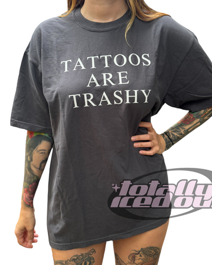 a woman wearing a tattoo t - shirt with the words tattoos are trashy on