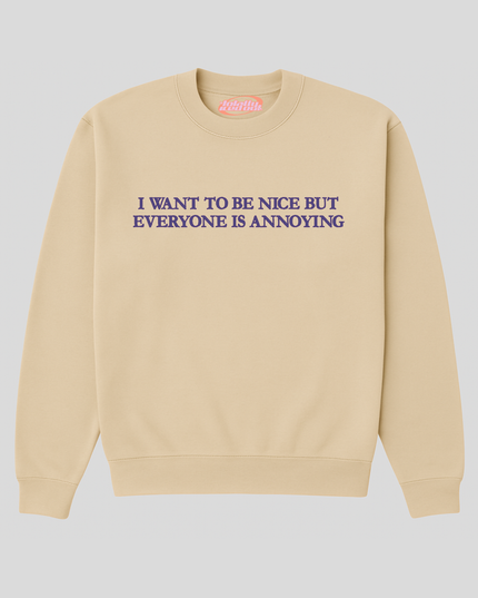 A beige sweatshirt with the text "I WANT TO BE NICE BUT EVERYONE IS ANNOUNCING" printed on it.