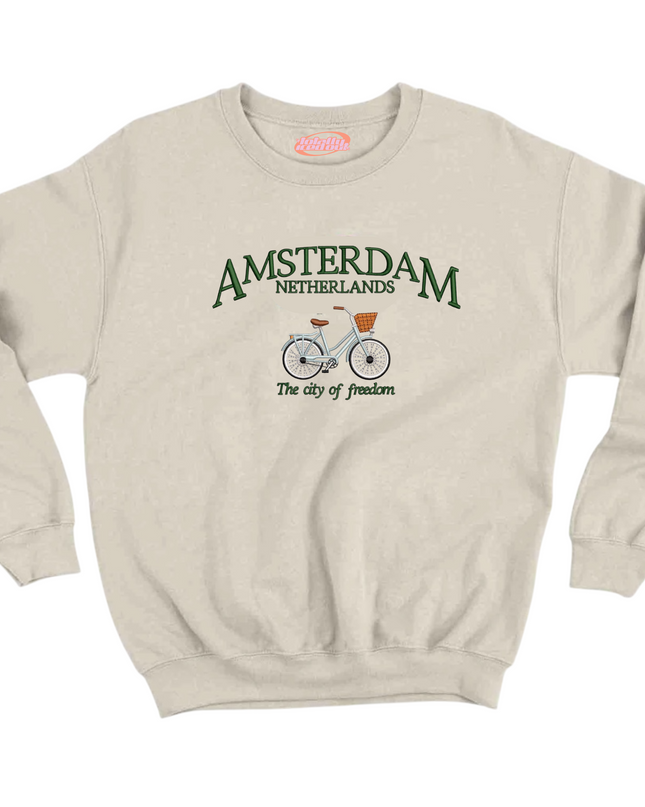 A beige sweatshirt with a graphic design featuring a bicycle and the text "Amsterdam Netherlands" and "The city of freedom".