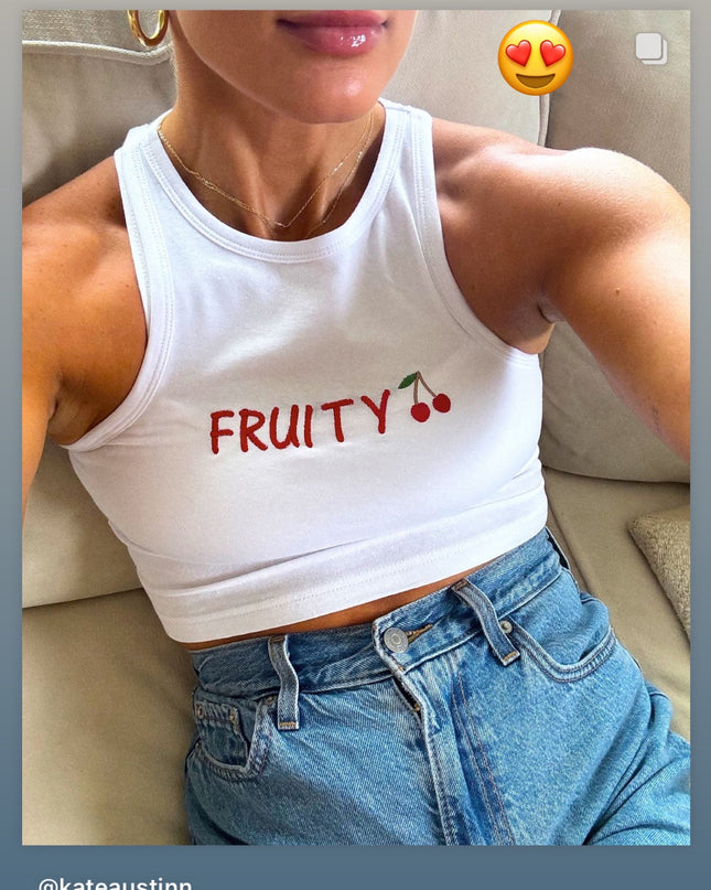 a woman wearing a white crop top with fruit on it